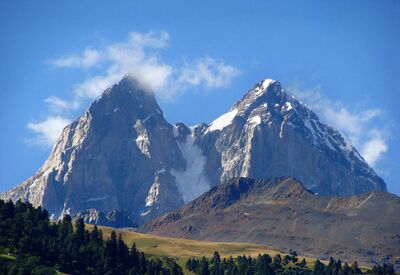 Bei geführten Wanderungen im Kaukasus tauchen die Gipfel des Ushba auf